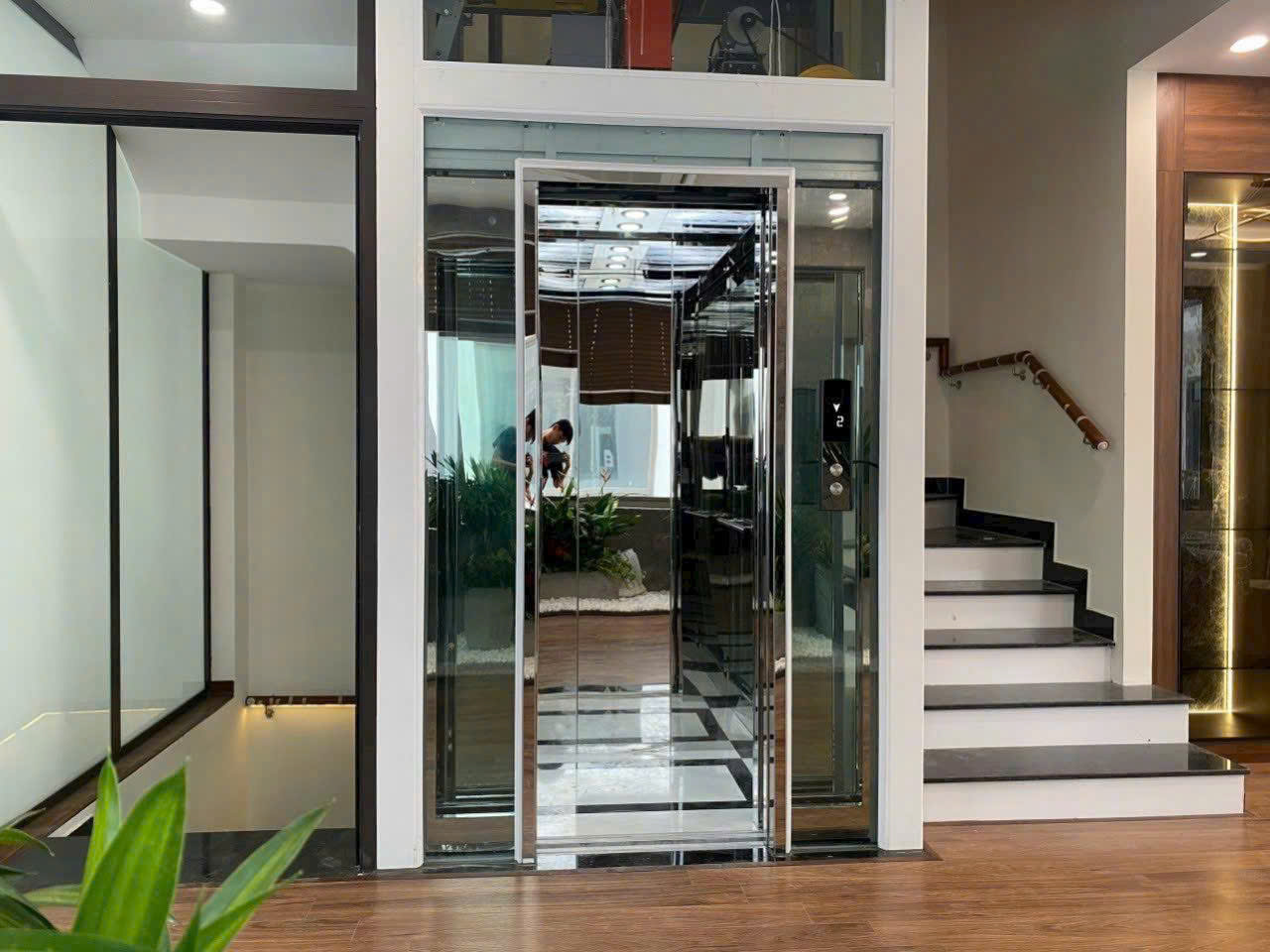 Thang máy kính gia đình hiện đại đặt cạnh cầu thang trong không gian nhà ở sang trọng